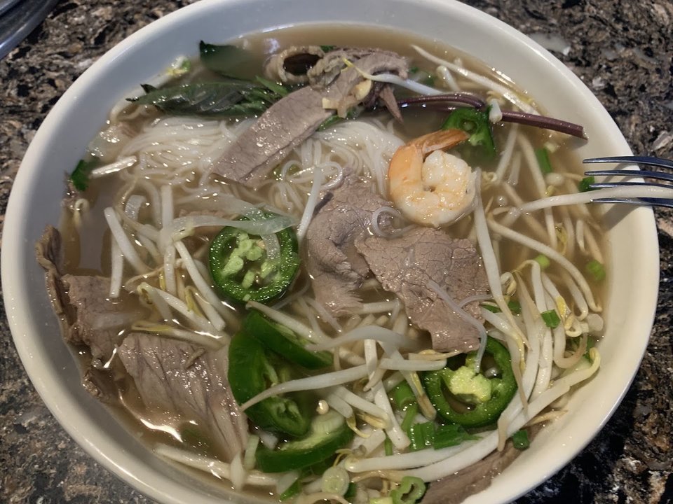 Plated pho beside small side dishes.